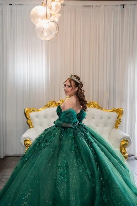 Quinceañera in emerald gown on gold throne chair at our Orem, Utah event venue