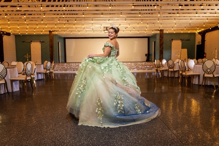 Quinceañera in green gown twirling at our Orem, Utah event venue