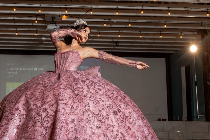 Quinceañera in pink gown on stage, crown and lights at our Orem, Utah event venue