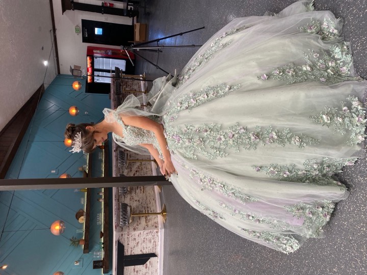 Quinceañera in sage gown, venue backdrop at our Orem, Utah event venue