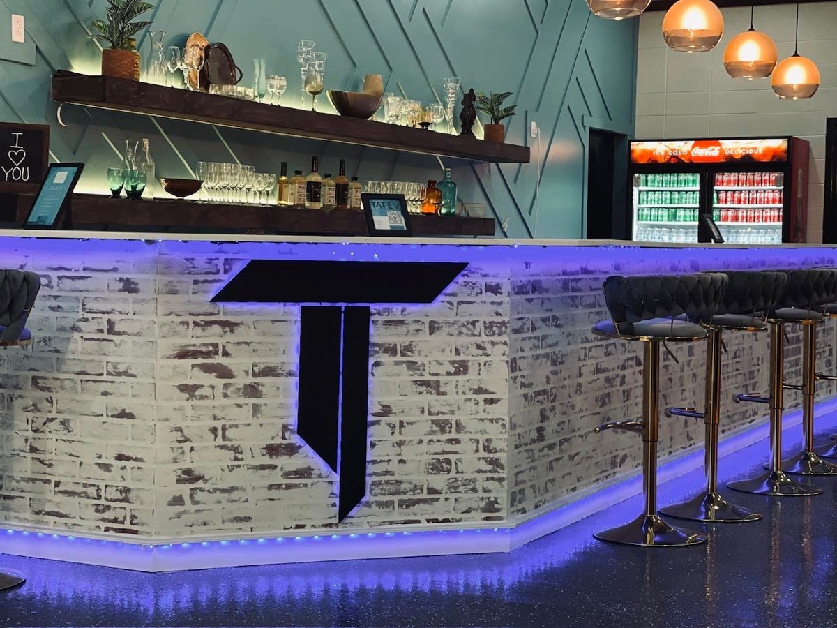 The venue bar with white brick, gold stools, and purple accent lighting at our Orem venue