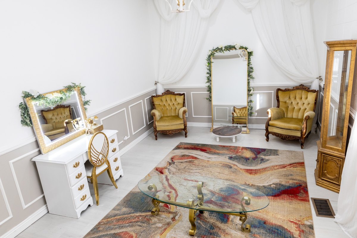 The bridal suite with gold velvet chairs, a vanity, and a floral arch at our Orem, Utah wedding venue