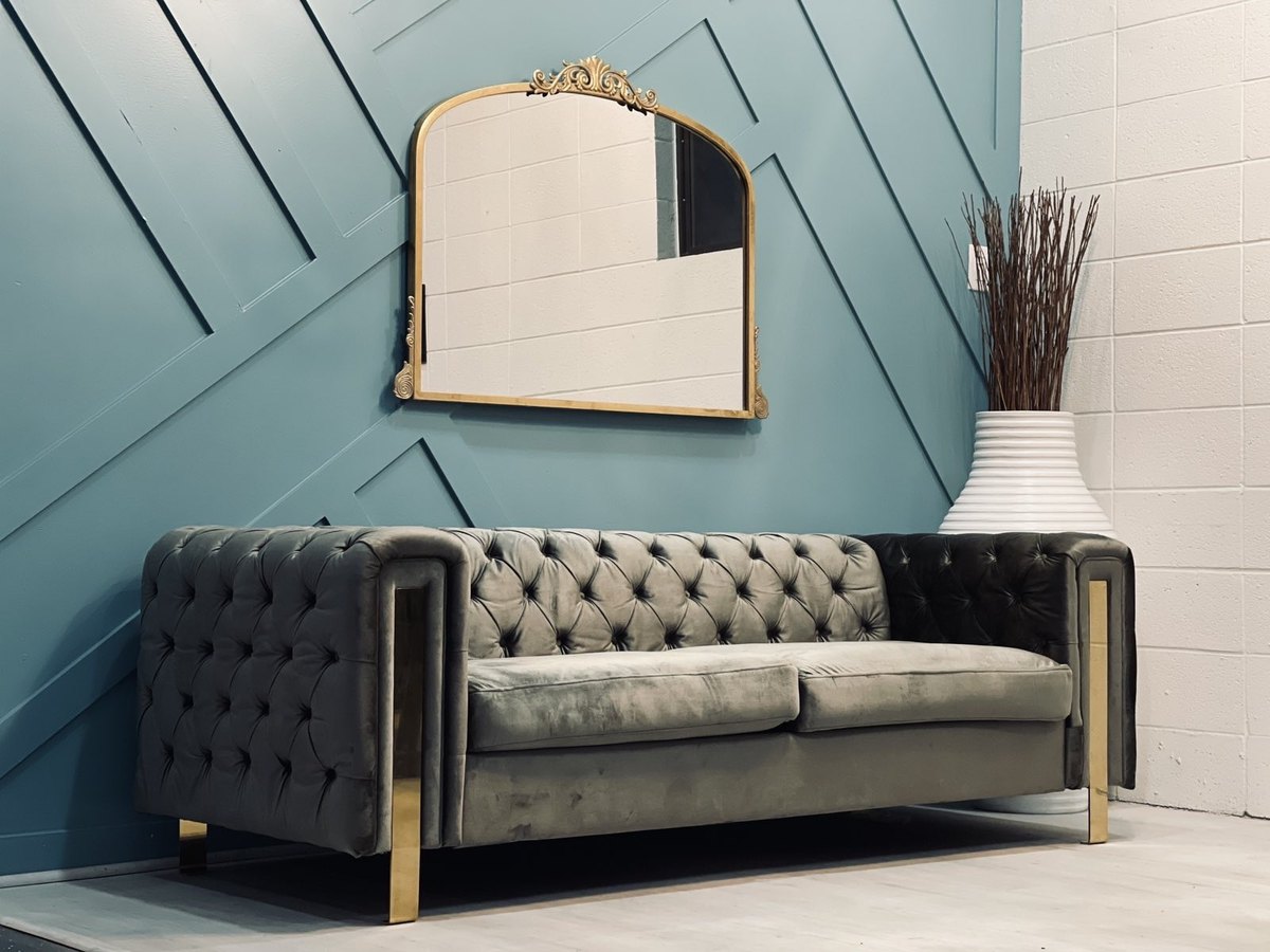 A gold mirror above a gray velvet lounge sofa at our Orem, Utah venue