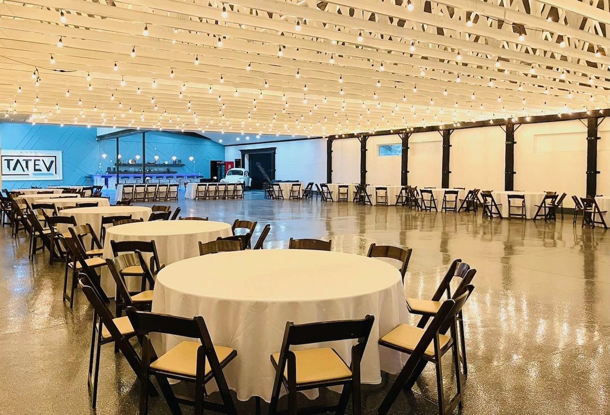 Round guest tables under string lights in the main hall at our Orem, Utah event venue